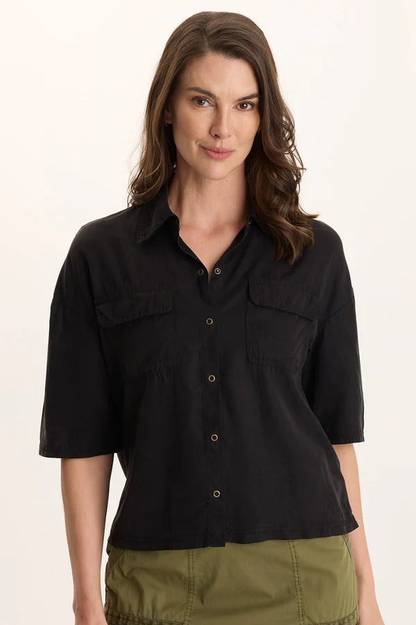 Woman wearing a black shirt with short sleeves on a plain background