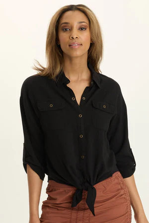Woman wearing a black shirt with rolled-up sleeves on a beige background