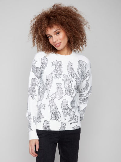 Woman wearing a white sweater with black animal pattern on a gray background